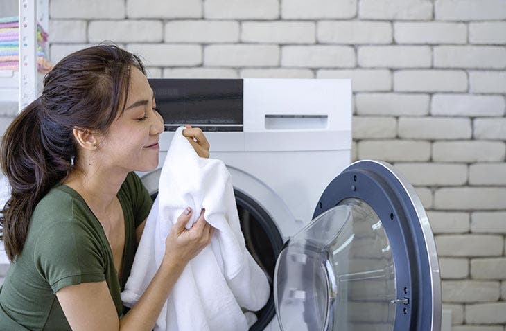 Femme appréciant l’odeur de son linge Femme appréciant l’odeur de son linge